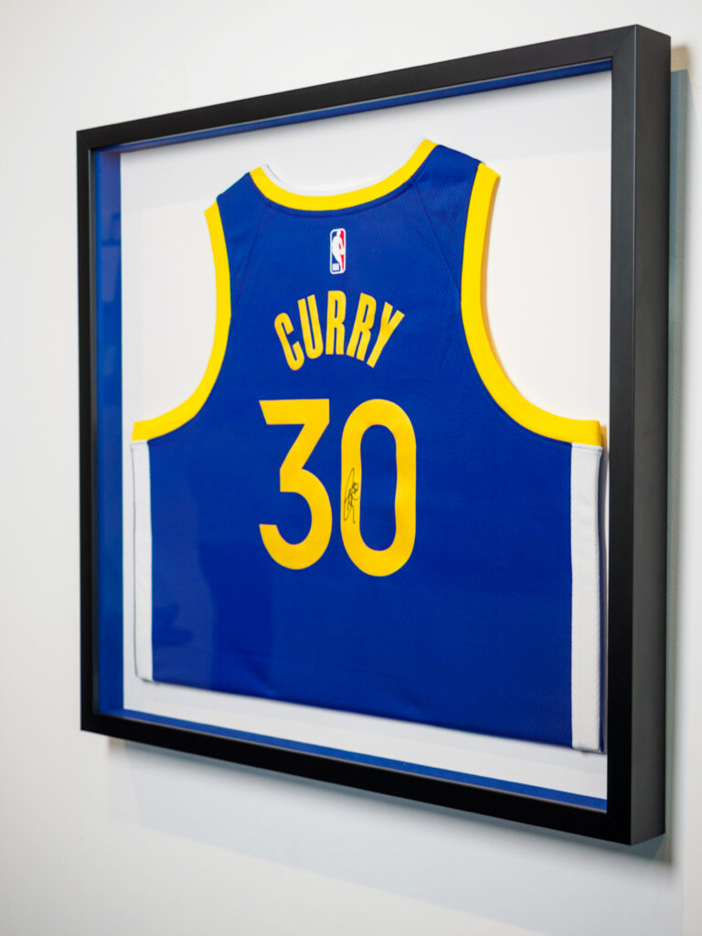 Stephen Curry signed Warriors jersey in custom shadowbox with Warriors blue interior walls, sports jersey framing Castro San Francisco